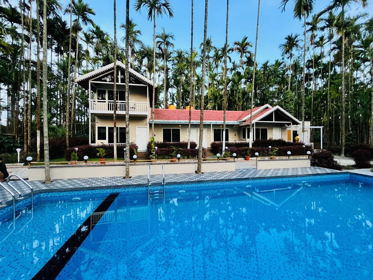 Swimming pool in front of the two-storey cottage, with areca palms behind